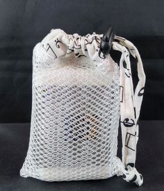 a white mesh bag with musical notes on the front and sides, sitting on a black surface