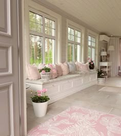 a living room filled with lots of furniture and flowers in vases on the windowsill