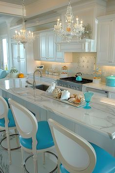 a kitchen filled with lots of white counter tops and blue chairs next to an island