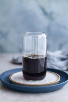 a glass filled with liquid sitting on top of a blue plate