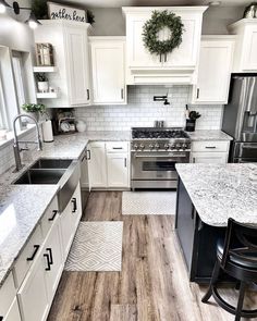 a kitchen with white cabinets and wood floors