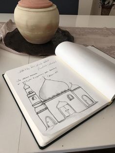 an open book sitting on top of a table next to a vase