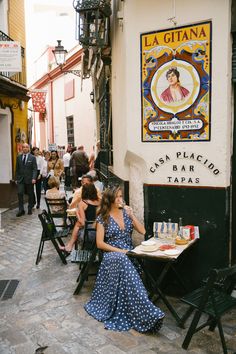 two women sitting at tables in front of a sign on the side of a building