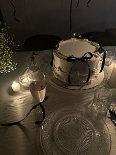 there is a cake on the table with candles and wine glasses next to it,