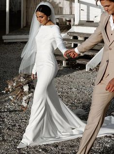 a bride and groom holding hands in front of a barn