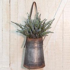 a metal bucket with flowers in it hanging on a wall