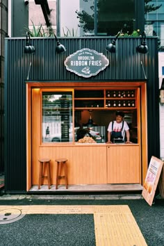 a man standing behind the counter of a restaurant in front of a building with an open door