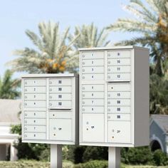 two mailboxes in front of a house with palm trees and bushes behind them