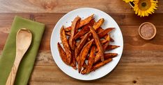 a white plate topped with sweet potato wedges next to a bowl of seasoning