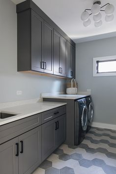 a washer and dryer in a room with grey cupboards on the wall