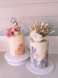 two decorated cakes sitting on top of white plates next to each other, one has flowers and the other is gold