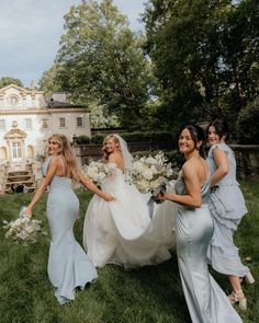 four bridesmaids walking in the grass with their bouquets and dresses flowing down