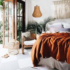 a bed room with a neatly made bed and lots of plants