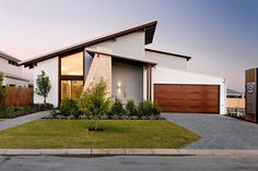 a modern house with grass and trees in the front yard