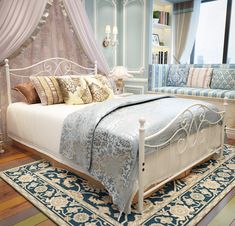 a white bed sitting on top of a wooden floor next to a blue and white rug