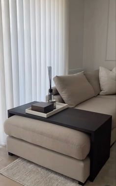 a living room with a couch, coffee table and white curtains