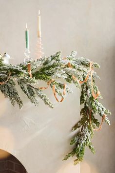 christmas decorations hanging from a mantel with candles