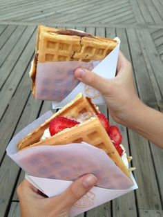 two people holding waffles with strawberries on them