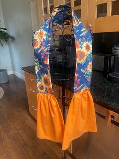 an apron with sunflowers on it hanging from a rack