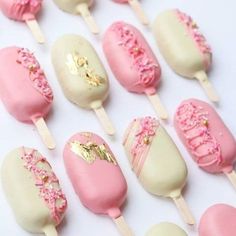 pink and white cake pops with sprinkles are arranged on a white surface