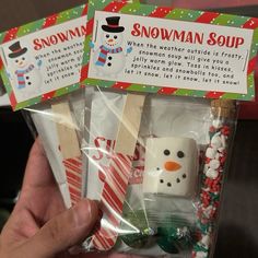 someone holding up two snowman soup cubes in their hand with candy on them