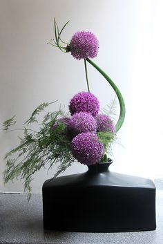 a black vase with purple flowers in it