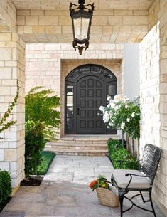 an entry way with a chair and potted plants on the side walk next to it