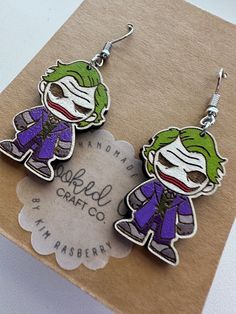 Welcome to our spooky collection of Handpainted Laser Cut Wood Dangle Earrings! These unique earrings are the perfect accessory for horror movie enthusiasts and Halloween lovers alike. 🔪 Key Features: 🎨 Handcrafted with precision: Each pair of earrings is meticulously handpainted and sealed, ensuring every detail of Joker is captured with precision and care.  All hardware is lead & nickel free. 👻 Statement piece: Make a bold statement and show off your love for horror with these eye-catching dangle earrings. They're perfect for Halloween parties, movie nights, or any day you want to embrace your inner horror fan. 💫 Lightweight and comfortable: Despite their size, these earrings are incredibly lightweight, making them comfortable to wear all day and night. 🎁 Perfect gift: Surprise your Joker Heath Ledger, Joker Heath, Heath Ledger Joker, Wood Dangle Earrings, Fan Jewelry, Halloween Lovers, Heath Ledger, Themed Jewelry, Halloween Jewelry