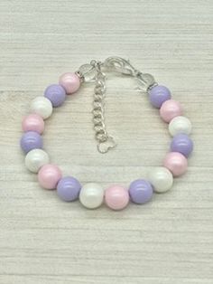 a pink, white and purple beaded bracelet on a wooden surface with a silver chain