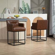 two brown chairs sitting next to each other on top of a hard wood floored floor