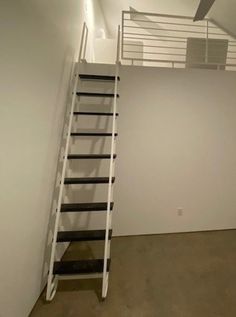 an empty room with white walls and a ladder leading up to the second floor window