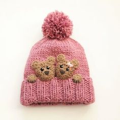 a pink knitted hat with two teddy bears on it