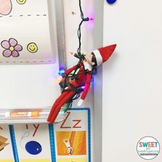 an elf is hanging on the wall with christmas lights