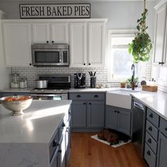 a dog laying in the middle of a kitchen with white cabinets and gray counter tops