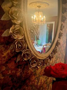 a mirror that is on the side of a wall with flowers in front of it