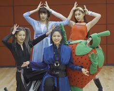 four young women are posing for a photo with their arms in the air while wearing costumes