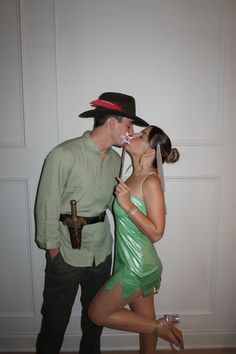 a man and woman dressed in costumes kissing each other while standing next to a wall