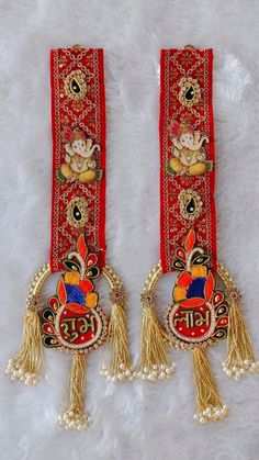 pair of red and gold decorated long tassels on white furnishing with two cherubs