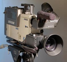 a camera with a lens attached to it's body is shown in front of a blue wall