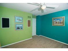 an empty room with green walls and pictures on the wall