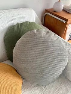 three pillows are sitting on a white couch