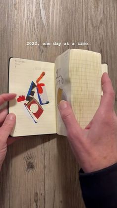 a person holding an open book with drawings on it and writing in the pages next to them