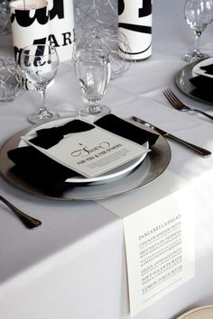 the table is set with black and white place settings, silverware, and napkins