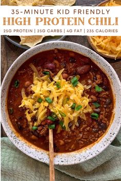 a white bowl filled with chili and cheese next to tortilla chips on a wooden table