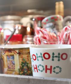 a coffee cup with candy canes in it on a shelf next to other christmas items