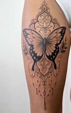 a woman's thigh with a butterfly tattoo on the side and an intricate design