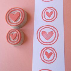 two rubber stamps with hearts on them sitting next to a white and pink bookmark