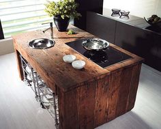 a kitchen island with two bowls on it and a stove top in the middle that is made out of wood