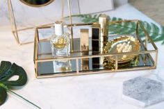 a table topped with mirrors and candles on top of a white table covered in greenery