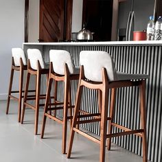 four bar stools are lined up in front of an island with white counter tops